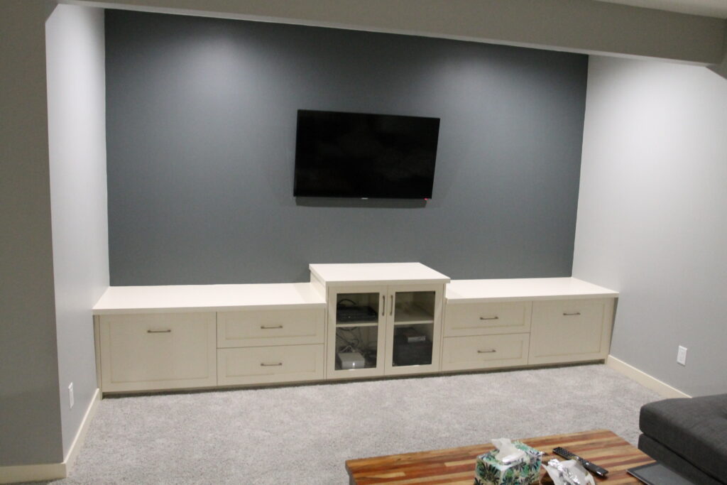 Custom built-in media cabinetry with a glass-door centre unit below a wall-mounted TV